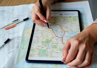 An overhead image showing a person tracing a route on a map with a finger, representing planning and choosing a bicycle commute path.